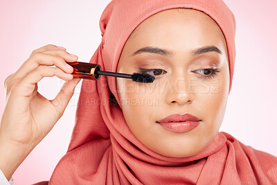 Buy stock photo Beauty, makeup and mascara with a muslim woman closeup in studio on a pink background for cosmetics. Luxury, eyelash and brush with a young islamic model getting ready to apply cosmetics to her face