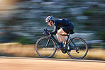 Motion blur, speed and cyclist on bicycle on road in mountain with helmet, exercise adventure trail and fitness. Cycling race, nature and man with bike for fast workout, training motivation or energy