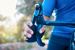 Cycling, person and hand on bike brakes for fitness, training and workout on blurred background in nature. Marathon, man and bicycle in zoom for sports exercise, performance and wellness outdoor