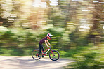 Blurred trees, sports and athlete cycling on bicycle for race, competition or marathon training. Fitness, fast and man cyclist riding a bike for speed practice challenge in mountain forest in nature.