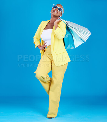 Buy stock photo Fashion, smile and black woman in studio with shopping, bag and glasses or excited for sale on blue background. Retail, store and African female customer happy with boutique, discount and mall deal