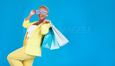 Buy stock photo Fashion, sale and black woman with shopping, bag and glasses in studio excited and smile on blue background. Retail, store and African female customer happy with boutique, discount and mall deal