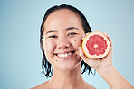 Portrait, smile or happy woman with grapefruit for skincare or beauty in studio on blue background. Results, dermatology or Asian person with natural fruits, vitamin c or glowing face for wellness