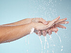 Woman, cleaning and hands with water splash in studio, blue background and healthcare mockup or washing in skincare. Model, closeup or hygiene with clean, soap or bubbles for protection from bacteria