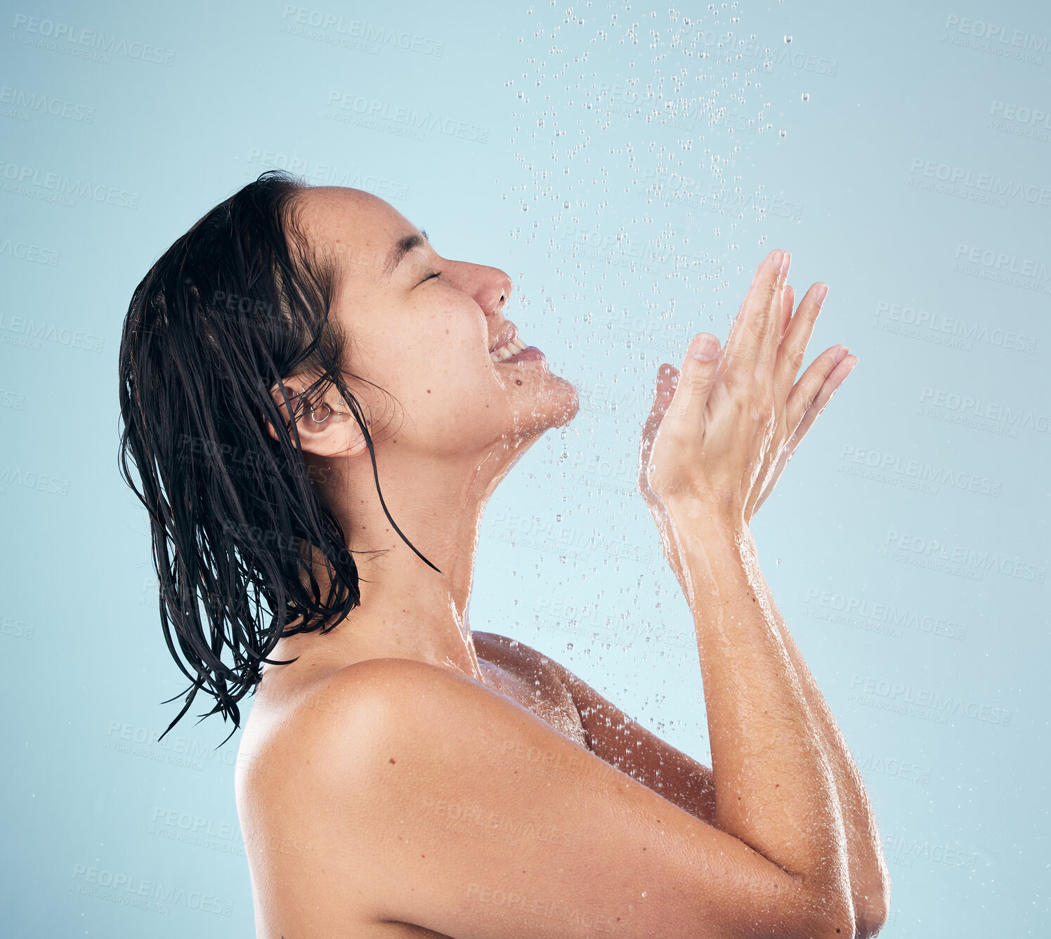 Buy stock photo Skincare, shower and woman smile cleaning in studio isolated on a blue background. Water splash, hygiene and model happy, washing and bathing in wellness, healthy skin beauty of body in bathroom.