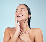 Skincare, shower and happy woman cleaning in studio isolated on a blue background. Water splash, hygiene and model smile, washing and bathing in wellness, healthy skin beauty of body in bathroom.