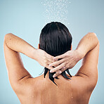 Skincare, shower and back of woman washing hair in studio isolated on a blue background. Water splash, hygiene and model cleaning, care and bathing for wellness of healthy skin, beauty or dermatology