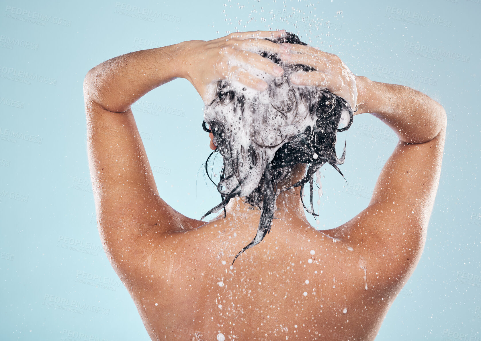 Buy stock photo Hair shampoo, cleaning and back of woman in shower in studio isolated on blue background. Water splash, hygiene and soap, foam or cosmetics of model washing, bath or wellness in body care in bathroom