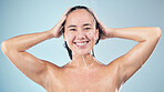 Face, shower and woman smile washing hair in studio isolated on blue background. Water splash, hygiene and portrait of natural Asian model happy, cleaning or bathing for wellness, beauty and cosmetic