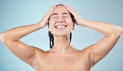 Buy stock photo Happy woman, shower and water drops in hygiene, washing or grooming against a blue studio background. Female person smile in relax body wash, cleaning or skincare routine under rain in bathroom