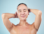 Skincare, shower and woman cleaning hair in studio isolated on a blue background. Water splash, hygiene and model washing, cosmetic and bathing in wellness, healthy skin or beauty of body in bathroom