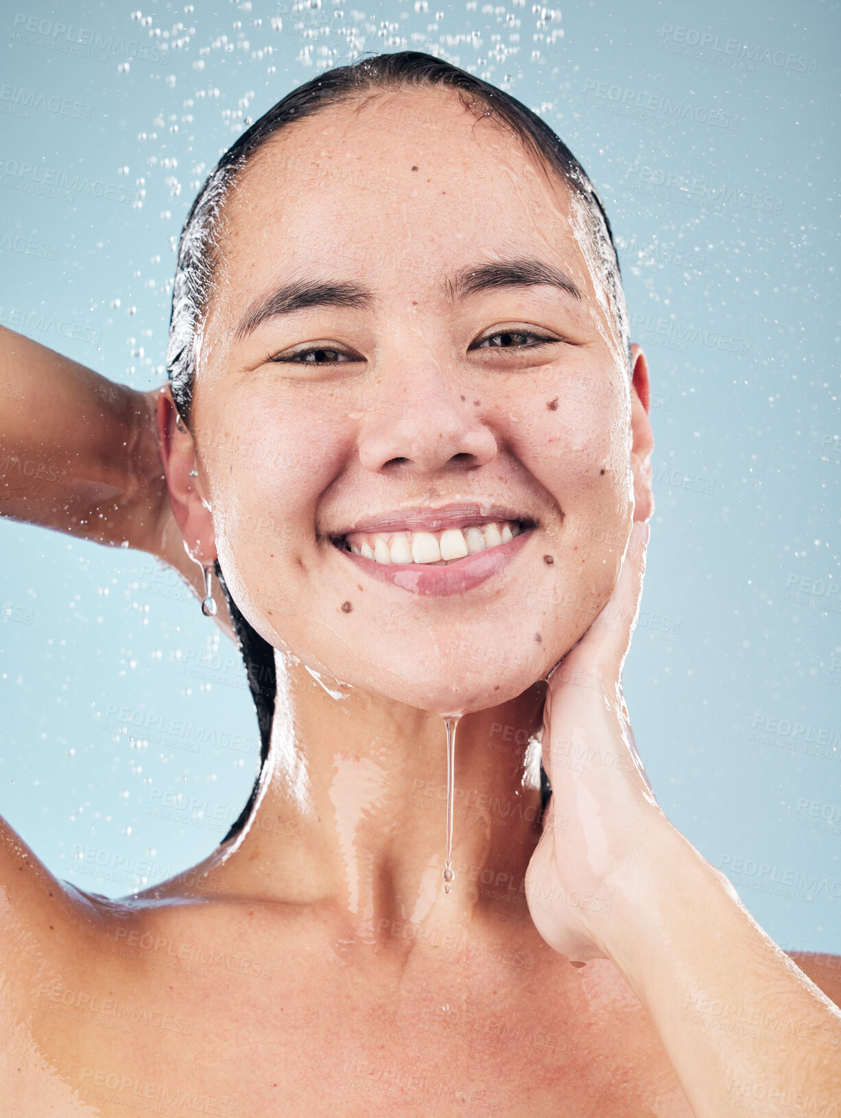 Buy stock photo Skincare, water splash and face of woman cleaning in studio isolated on a blue background. Shower, hygiene and portrait of happy Asian model washing, cosmetic and bath for wellness, health and beauty
