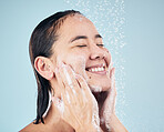 Skincare, shower soap and happy woman cleaning in studio isolated on a blue background. Water splash, hygiene foam and model smile, washing and bathing in wellness, healthy skin or beauty in bathroom