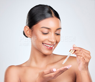 Buy stock photo Smile, skincare and a woman with oil on a white background for wellness, glow or hydration. Happy, dropper and an Indian model or person with liquid collagen for beauty, dermatology or serum