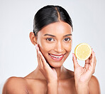 Portrait, beauty and lemon with a natural woman in studio on a white background for vitamin C nutrition. Face, skincare and fruit with a happy young model looking confident in organic treatment