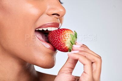 Buy stock photo Health, closeup and woman eating strawberry in a studio for healthy diet snack for nutrition. Wellness, beauty and zoom of female model with fruit for natural skin detox routine by a gray background.