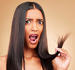 Hair care, shock and portrait of woman in a studio with split ends for salon keratin treatment. Beauty, cosmetic and surprised Indian female model with hairstyle isolated by a brown background.