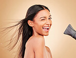 Wink, hair and portrait of happy woman with hairdryer for beauty isolated in a studio brown background with strong texture. Aesthetic, glow and young person with heat protect for health and shine