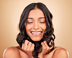 Hair care, happy and young woman in a studio with healthy salon keratin treatment for self care. Beauty, cosmetic and headshot of Indian female model with hairstyle isolated by a brown background.