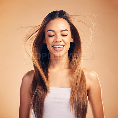 Buy stock photo Face, hair and wind with an aesthetic woman in studio on a brown background for shampoo treatment. Smile, beauty and keratin with a happy young model at the salon for growth or natural haircare