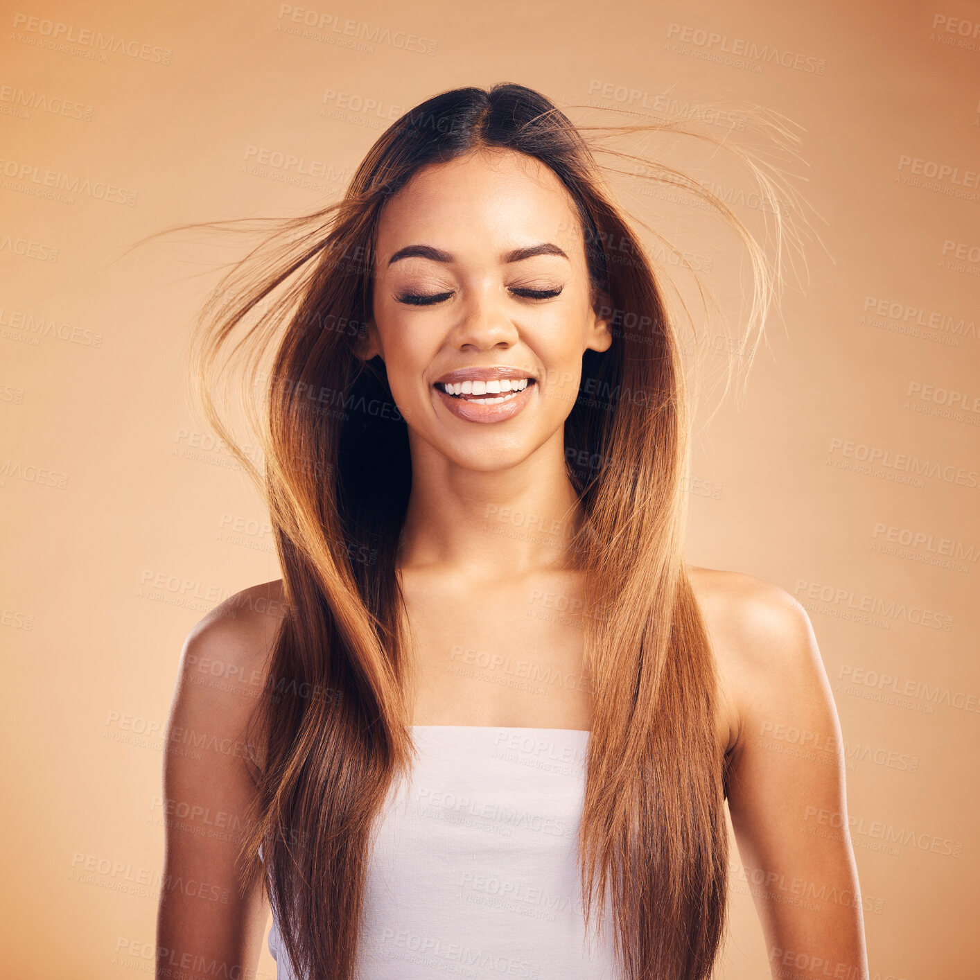Buy stock photo Face, hair and wind with an aesthetic woman in studio on a brown background for shampoo treatment. Smile, beauty and keratin with a happy young model at the salon for growth or natural haircare