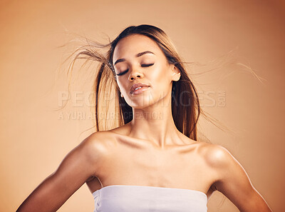 Buy stock photo Beauty, hair and wind with a natural model in studio on a brown background for keratin treatment. Skin, shampoo and body with a confident young woman at the salon for growth or aesthetic haircare