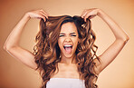Portrait, woman and excited for curly hair beauty isolated on a brown background in studio. Face, hairstyle and natural cosmetics of happy model in salon treatment for health, wellness or hairdresser