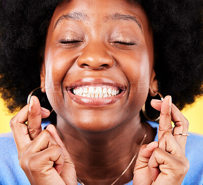 Buy stock photo Black woman, face and fingers crossed in studio for hope, trust and optimism of competition, prize and lottery. Happy model emoji for luck, bonus promotion and winning giveaway on yellow background