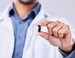 Closeup, hand and a hearing aid from a doctor for communication, medical support or service. Healthcare, sound and a person or surgeon with an ear piece for listening, audiology or helping with gear