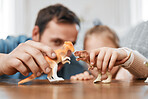 Playing, dinosaur and the hands of a father and child for bonding, childhood and on a table. Closeup, together and a man, dad or kid with a toy for happiness, entertainment or family in a house