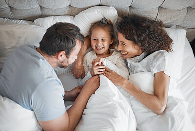 Buy stock photo Family, bed and parents laughing with their daughter in the morning to relax after waking up together. Kids, love or smile with a man, woman and cute child having fun in the bedroom from above