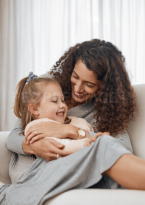 Buy stock photo Love, hug and mother with girl child on a sofa happy, playing and bonding in their home together. Family, smile and kid with mom in a living room embrace, relax and enjoy weekend, day off or break