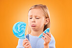 Children, candy and a sad girl with a broken lollipop on an orange background in studio looking upset. Kids, sweets and unhappy with a female child holding a cracked piece of a sugar snack in regret