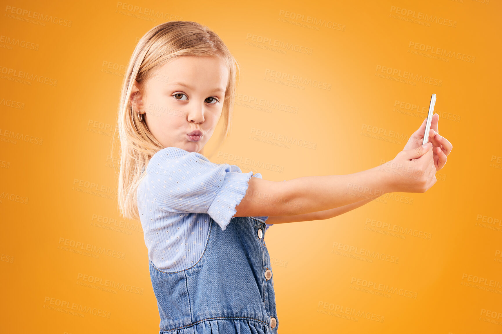 Buy stock photo Phone, selfie or portrait of child in studio with confidence or mockup space in photograph memory. Kid, orange background or face of girl taking picture online on a social media app on internet