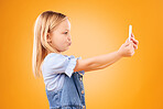 Phone, selfie or profile of kid in studio with confidence or mockup space in photograph memory. Post, orange background or young girl child taking picture online on a social media app on internet