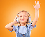 Headphones, happy or child streaming music to relax with freedom in studio on orange background. Hand up, singing or girl singer listening to a radio song, sound or gospel on an online subscription