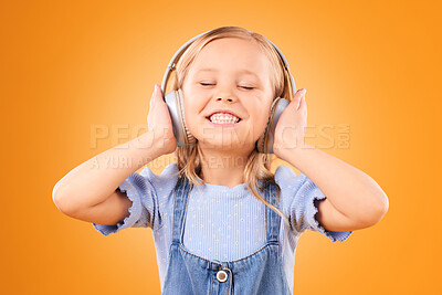 Buy stock photo Headphones, smile or child streaming music to relax with freedom in studio on orange background. Face, singing or happy girl singer listening to a radio song, sound or audio on an online subscription