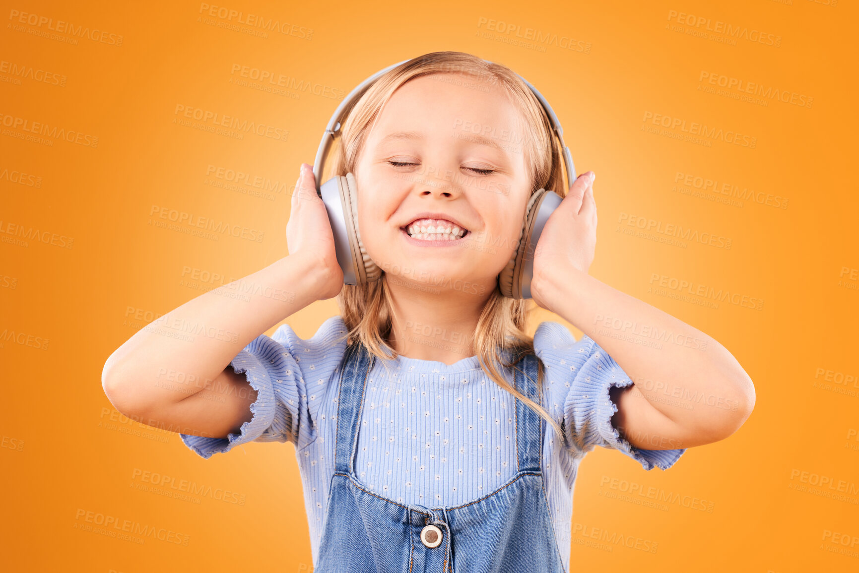 Buy stock photo Headphones, smile or child streaming music to relax with freedom in studio on orange background. Face, singing or happy girl singer listening to a radio song, sound or audio on an online subscription