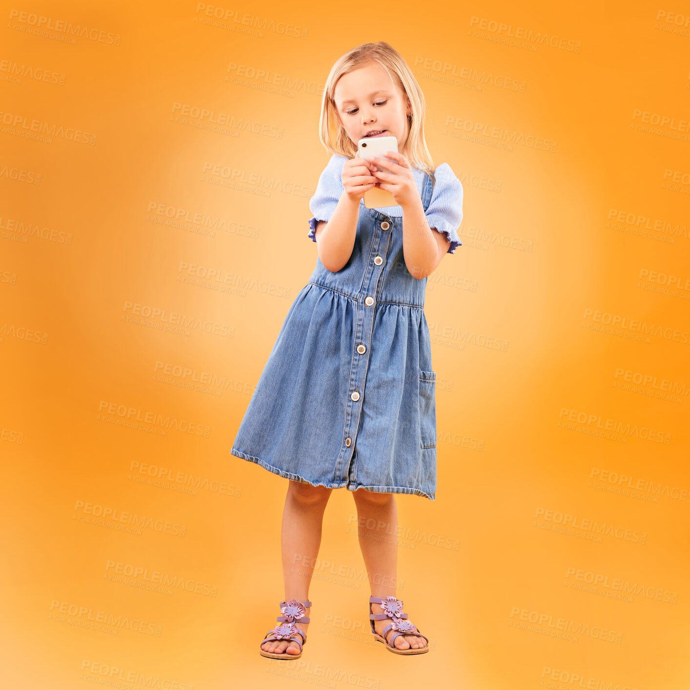 Buy stock photo Girl, child and typing with phone in studio for social media, play mobile games and download app on orange background. Young kid scroll smartphone to search website, watch multimedia and subscription