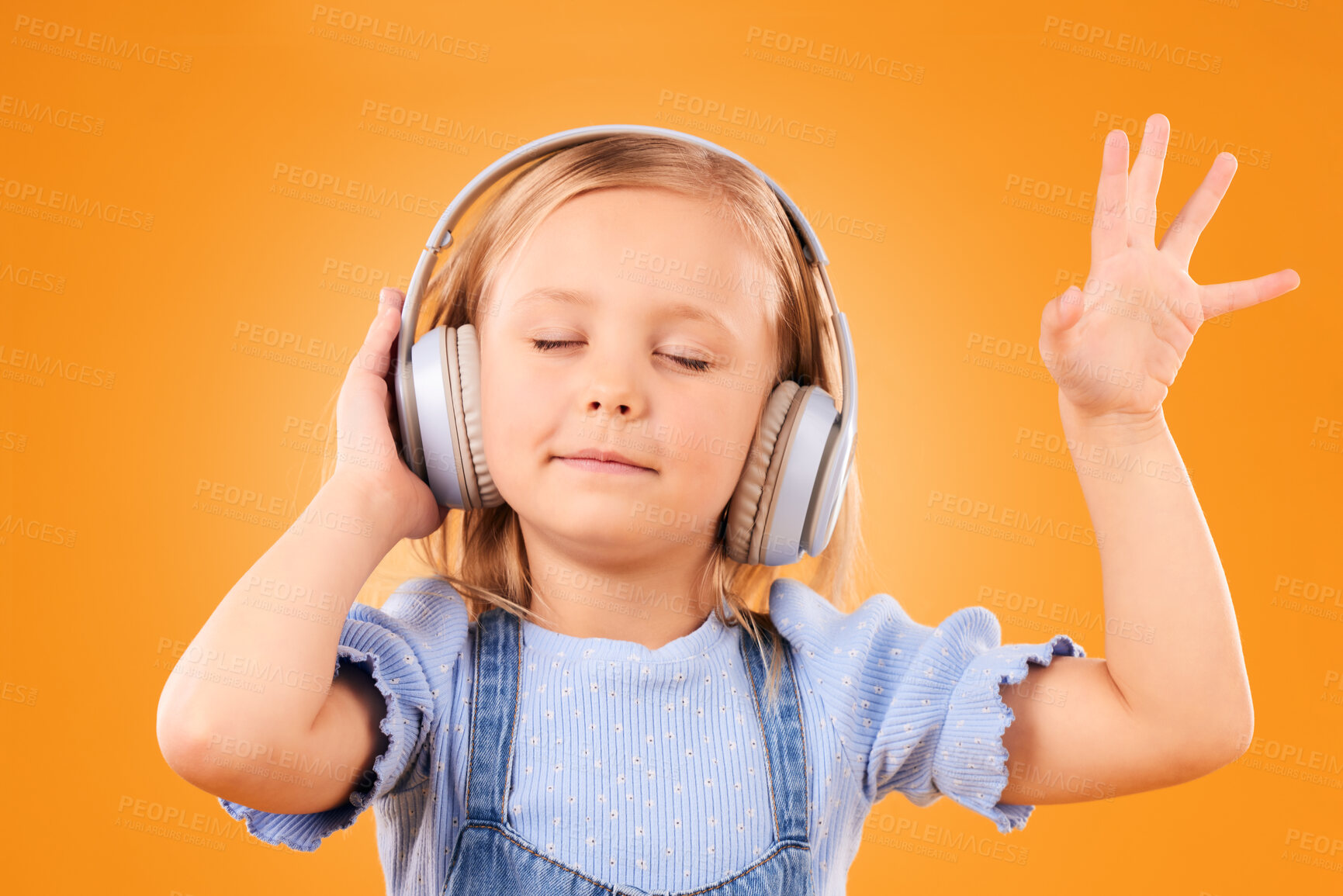 Buy stock photo Child, headphones and dance to music in studio for freedom, multimedia subscription or kids podcast on orange background. Happy young girl listening to audio, streaming sound or hearing song on radio