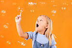 Girl child, surprise and pop bubbles, playing and fun with youth isolated on orange background. Liquid soap, wow and amazed with kid from Australia in studio, playful and toys with childhood 