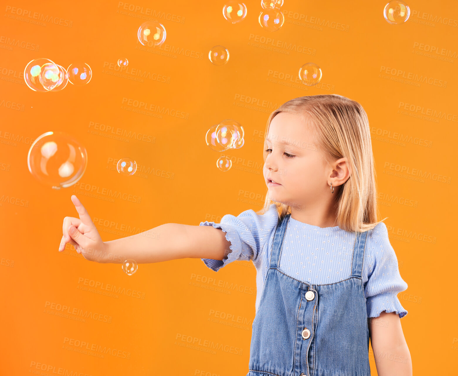 Buy stock photo Young girl child, pop bubbles and game, playing and fun with youth isolated on orange background. Liquid soap, development with kid from Australia in studio, playful and toys with childhood 