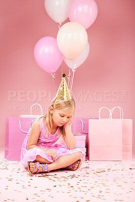 Depression, sad birthday and girl on pink background for party, celebration and festive event in studio. Upset, emotion and unhappy, lonely and young child on floor with balloons, presents and gifts