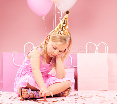 Depression, sad birthday and child on pink background disappointed for party, celebration and event. Lonely, emotion and unhappy, lonely and upset girl with balloons, presents and gifts in studio