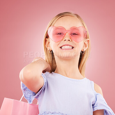 Buy stock photo Girl, child and portrait, fashion sunglasses with shopping bag or gift, event and happiness on pink background. Stylish, retro and accessory with funky outfit, present for party or retail in studio 