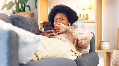 Buy stock photo Phone, social media and yawn with a black woman on a sofa in the living room of her home to relax. Mobile, communication and tired with an exhausted young person lying on a couch during the weekend