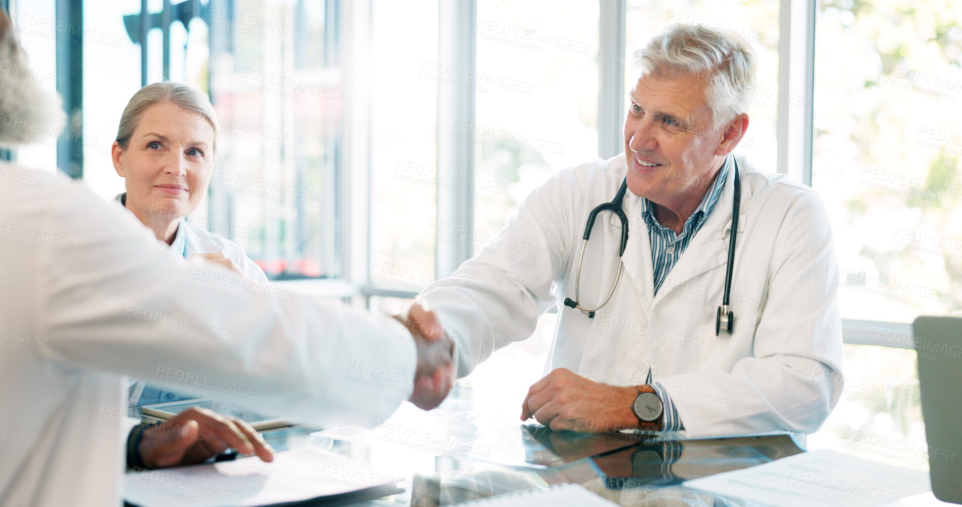 Buy stock photo Interview, doctors shaking hands and partnership with team in meeting at hospital, senior physician and agreement. Solidarity, support and healthcare collaboration with medical professional people