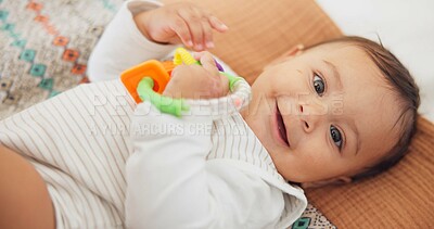 Cute, playing and sweet baby with a toy on a blanket for child development, fun and entertainment. Happy, sweet and portrait of a playful infant child relaxing on a bed in his nursery or bedroom.