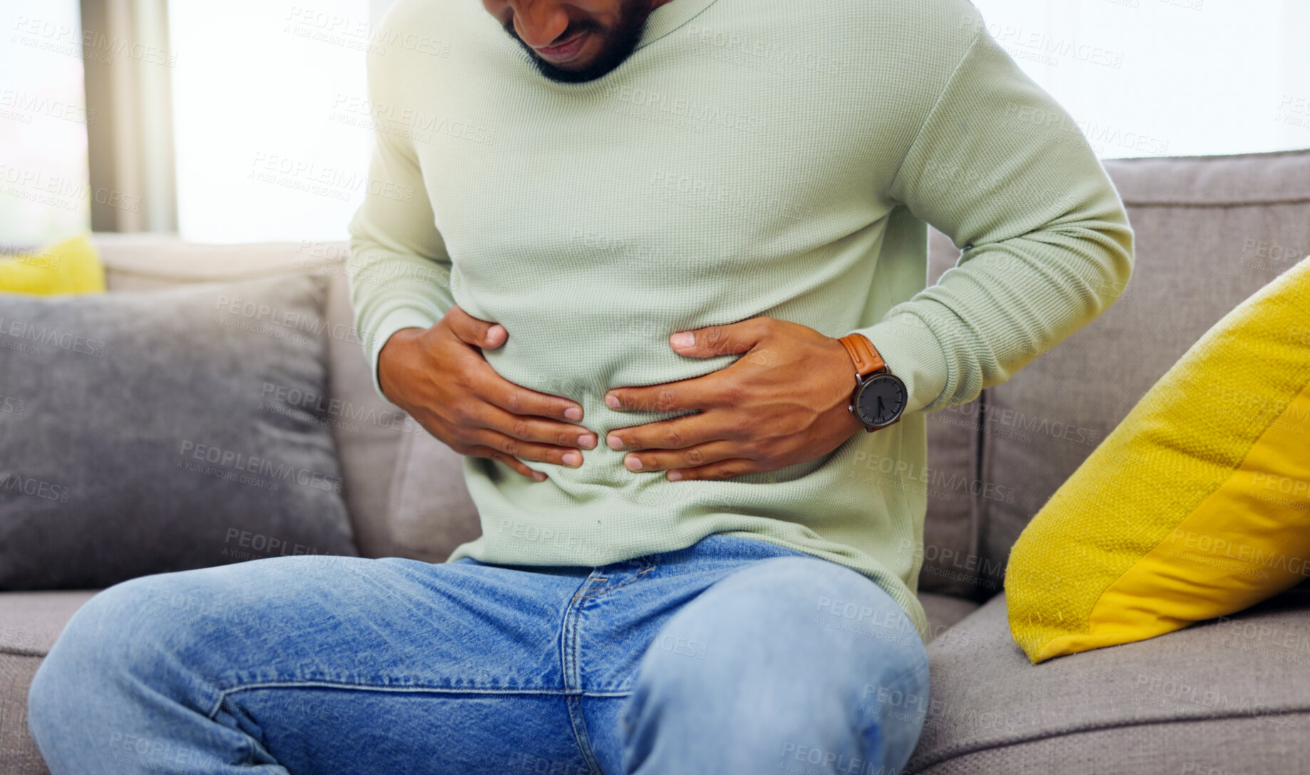 Buy stock photo Man on a sofa with stomach pain, sickness or cramps while relaxing in the living room at his home. Medical emergency, illness and male with diarrhea, indigestion or food poisoning ache at his house.