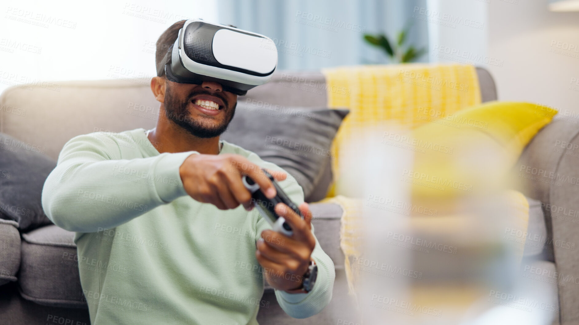 Buy stock photo Vr, gaming Indian man in virtual reality in home on sofa in living room, laughing and having fun. 3d metaverse, esports gamer and happy young male playing futuristic games with controller